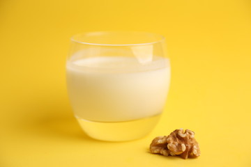 glass of walnut milk in color background