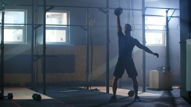 A man in the gym performs a pull-up dumbbell in slow motion.