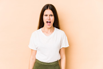 Obraz premium Young caucasian woman isolated on beige background shouting very angry, rage concept, frustrated.