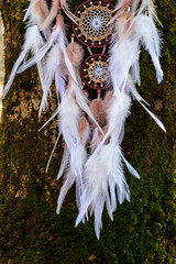 Handgefertigter Traumfänger mit Federn, Fäden und Perlen am Seil hängend © dashtik