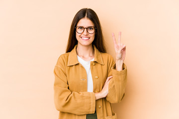 Young caucasian woman isolated on beige background showing number two with fingers.