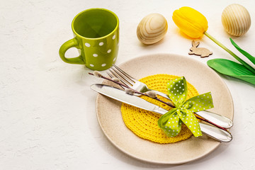 Easter table setting on textured white putty background. Spring holiday card template. Cutlery,...