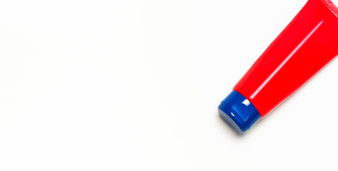 Red clean empty tube of cream or gel for hands, face, body on white background. Flat lay top view copy space. Mock-up of cosmetics spa cream bottles container. Template for design and logo application