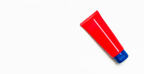 Red clean empty tube of cream or gel for hands, face, body on white background. Flat lay top view copy space. Mock-up of cosmetics spa cream bottles container. Template for design and logo application