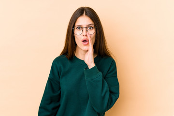 Fototapeta premium Young caucasian woman isolated on beige background is saying a secret hot braking news and looking aside