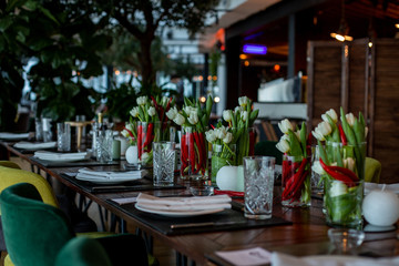 horizontal photo of a dining table decorated with candles and unusual flower arrangements
