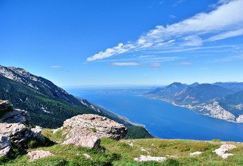 Malcesine, Italy - Monte Baldo, cliffs and mountains covered with greenery and trees, below the blue Lake Garda, in the summer afternoon.