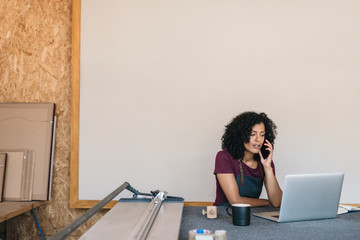 Young woman talking on the phone in her framing studio