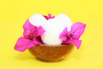 festive white eggs and natural flowers of pink bougainvillea in decorative wooden plate