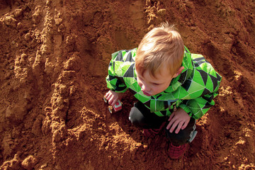 A child plays with a wooden machine in the sandbox