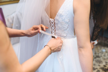 Obraz na płótnie Canvas bridesmaid tying know on wedding dress
