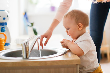 Toddler with mom wash their hands in the sink