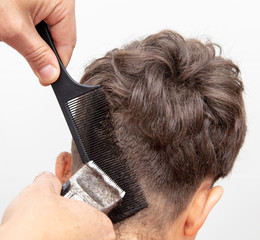 The hairdresser cuts the hair of a boy with a machine
