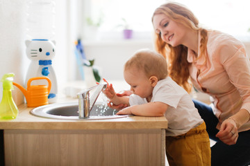 Toddler with mom wash their hands in the sink