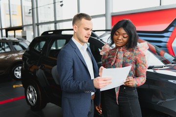 beautiful young african woman buying a car at dealership