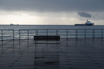 Fototapeta na wymiar Promenade benches after rain and cloudy sky