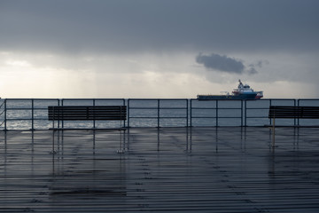 Fototapeta premium Promenade benches after rain and cloudy sky