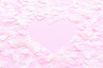 Heart made of pink confetti on pastel background. Festive romantic gentle abstract background for the design. Valentine's Day. Top view, flat lay composition. Copy space for text.