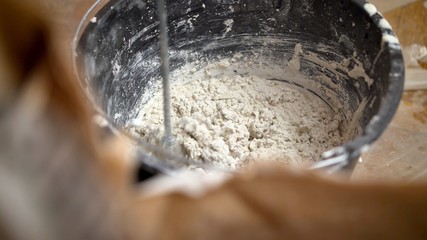 Construction worker man stirs the mixture in the bucket construction for alignment a