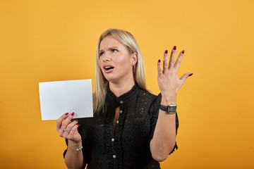 Beautiful blonde girl in black dress on yellow background an irritated woman shows clean white...