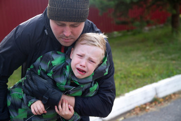 The man grabbed and caught the little boy.  The boy cries and struggles.