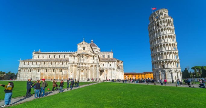 Pisa, Tuscany, Italy - February 3, 2020: Piazza dei miracoli of Pisa. Travelers admire architecture of the Cathedral and  the iconic leaning tower of Pisa. Clear Blue sky