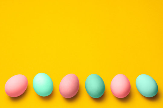 easter eggs painted in pastel colors on a yellow background with copyspace. easter advertise minimalist concept design