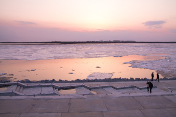 picturesque colorful ice drift on a calm wide river during the pink sunset with pink reflection on water
