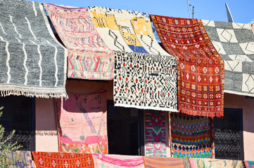 Moroccoan colorful carpets and blankets, cushions hanging at the souks and market places in Morocco