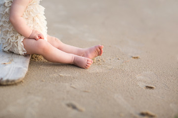 Child feed on a beech sand. baby's bare legs