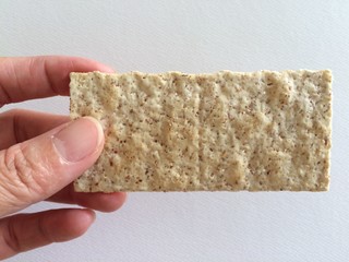 In the hand there is a light yellow crispy snack, a snack on a white background.