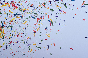 Multi colored shavings of pencils on a white paper. Abstract background.