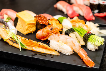 Real Japanese sushi in a restaurant in Tokyo. Set of sushi on a black plate made of stone.