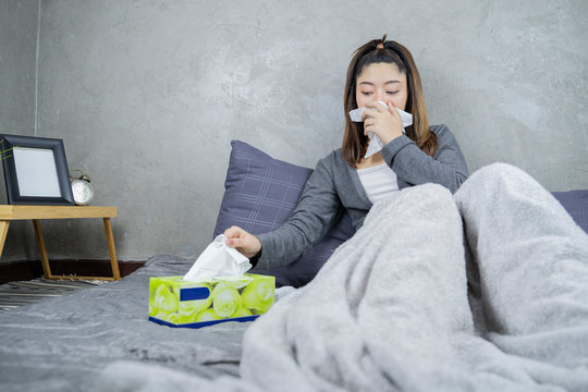 Sick day at home. Asian woman has runny nose and common cold. Cough. Beautiful Young Woman Caught Cold Or Flu Illness.