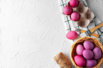 Painting Easter eggs in pink on white table, view from above