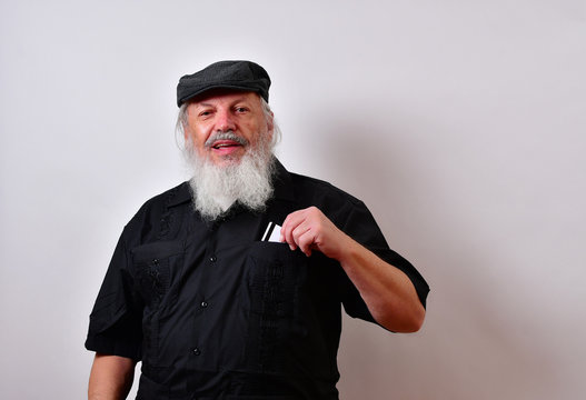 Old man making a payment with his credit card... .Mature gentleman with a newsboy cap and black guayabera shirt and long white beard..