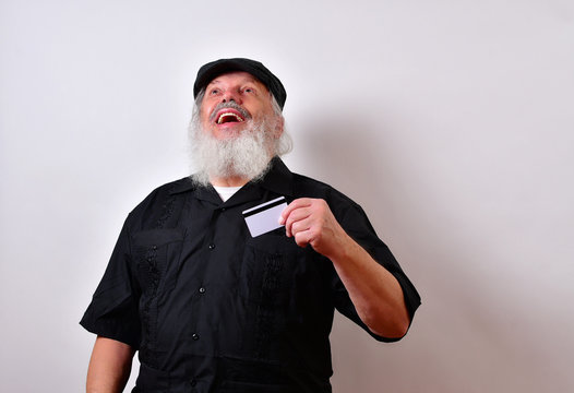Old man is thanking his lucky stars he found his lost credit card... .Mature gentleman with a newsboy cap and black guayabera shirt and long white beard..