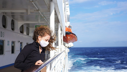 Curly girl in a medical respirator on board a cruise ship on a sunny day against the background of the sea. quarantined european girl on promenade deck of cruise ship 