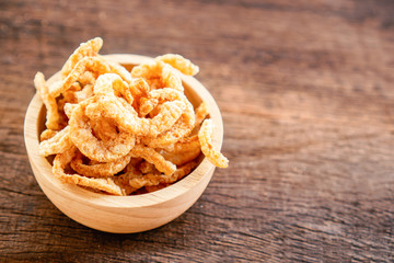 pork snack, rind, scratching or pork crackling in bowl on wooden table 