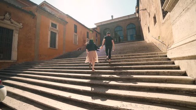 young couple holding hands running up stairs