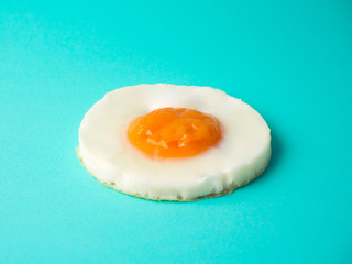 Perfect circle fried egg on blue-green background