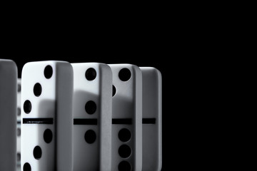 Dominoes standing in a row on black background