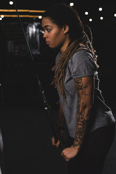 side view of african american girl with tattoo exercising in gym