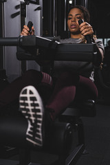 Fototapeta na wymiar selective focus of african american girl working out on gym machine