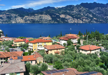 Fototapeta na wymiar Monte Baldo, Italy - Brown tiled houses and trees in the city of Malcesine, Blue Lake Garda, in the summer afternoon.