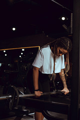 Obraz na płótnie Canvas attractive african american sportswoman exercising with barbell