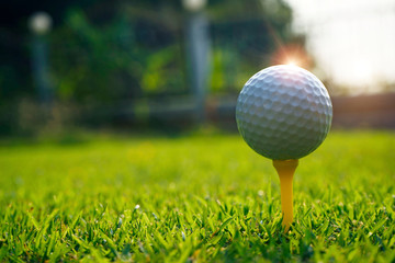Golf ball on tee in the evening golf course with sunshine.