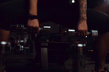 Cropped view of african american young adult squating with dumbbells