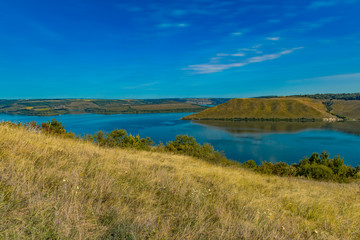 Fototapeta na wymiar summer panoramic idyllic nature landscape scenic view of river surrounded by hill land outdoor environment and blue sky horizon background space