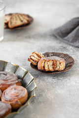 Cinnamon rolls or cinnabons with white cream glaze on a vintage plate. Cinnabon served on a gray table. Traditional homemade sweet buns. Selective focus, light tones, copy-space